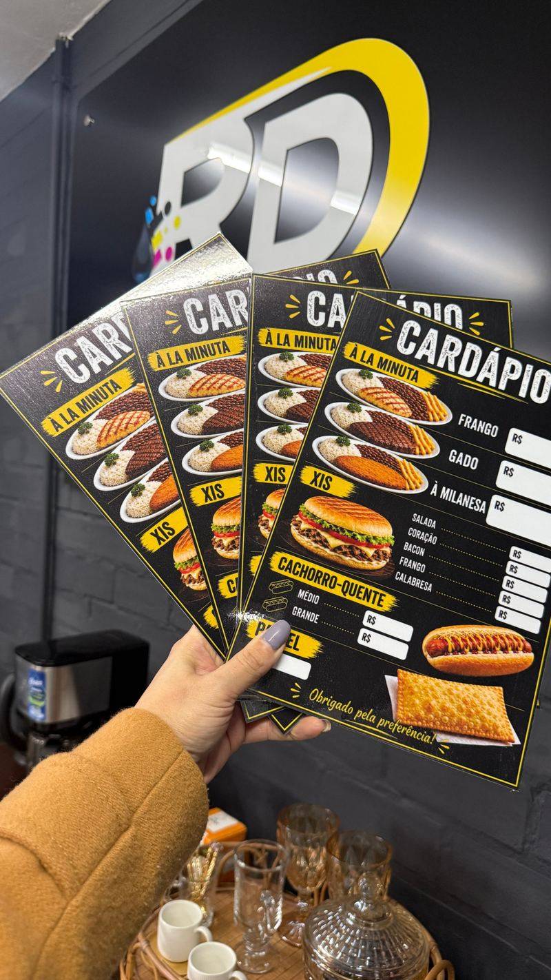 Cardápios impressos pela RD em frente à placa com a logo da empresa