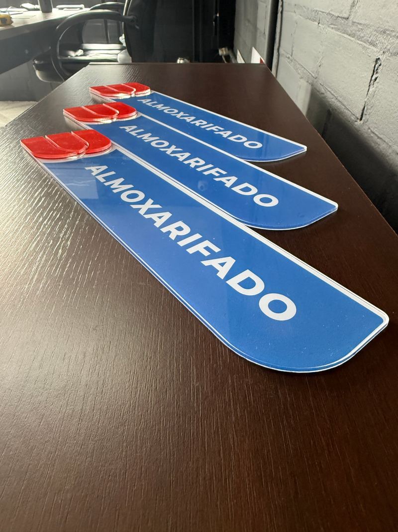 Três placas de identificação azuis em acrílico com a palavra almoxarifado, prontas para instalação