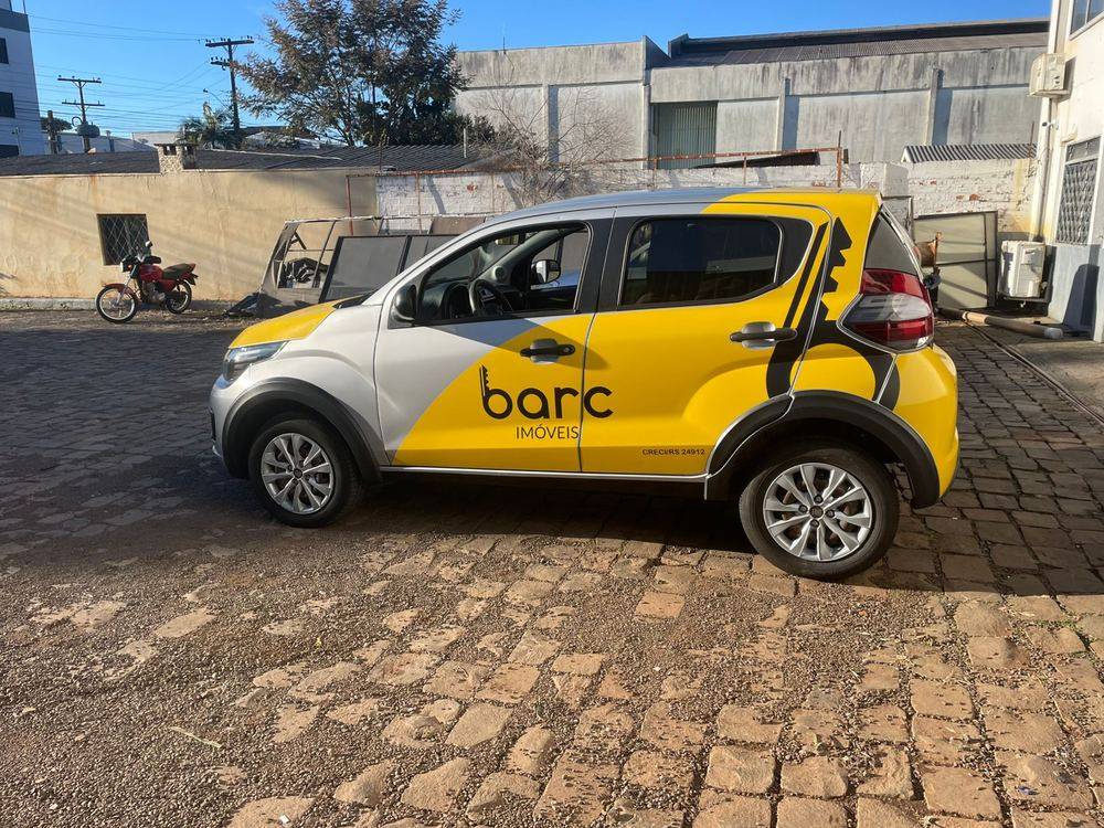 Carro com envelopamento nas cores amarelo, cinza e preto de uma imobiliária